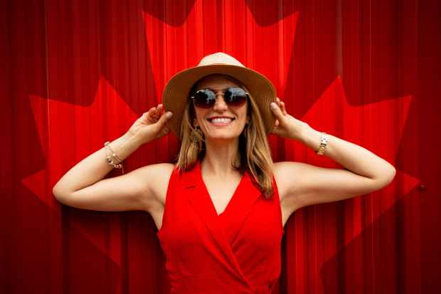 woman in red sleeveless dress with canada flag printed background